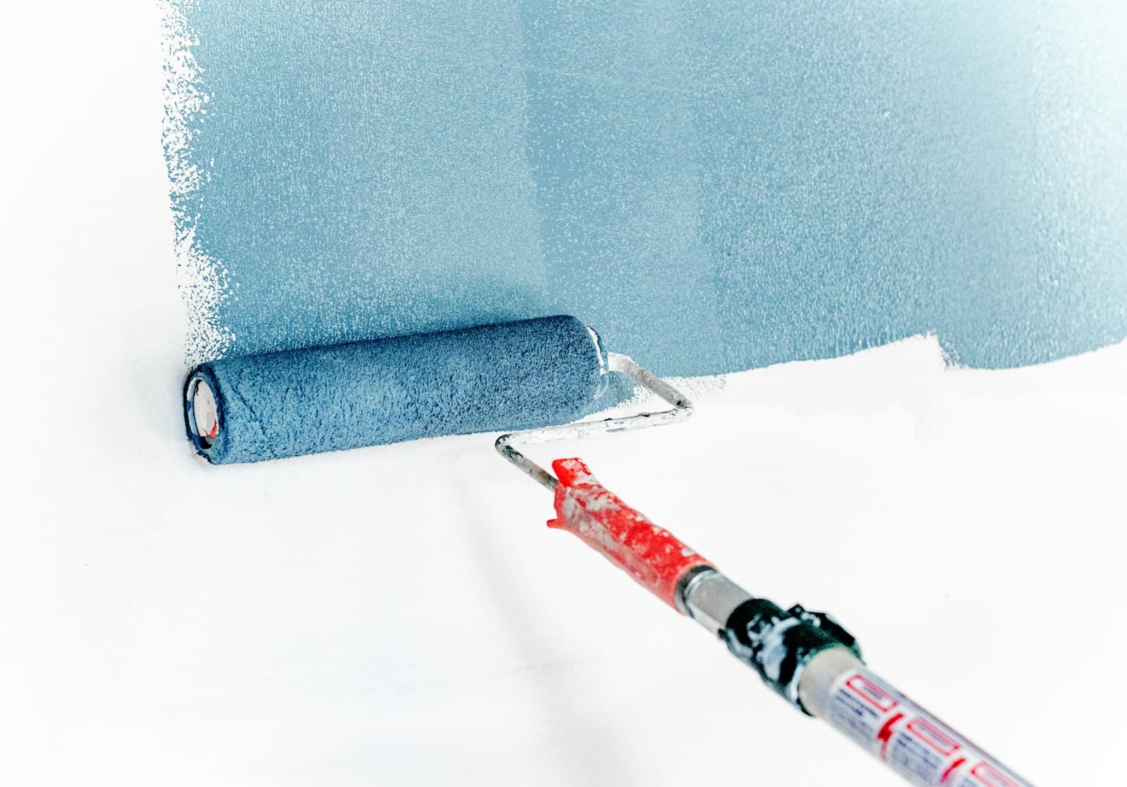 Paint roller applying a coat of paint to a wall